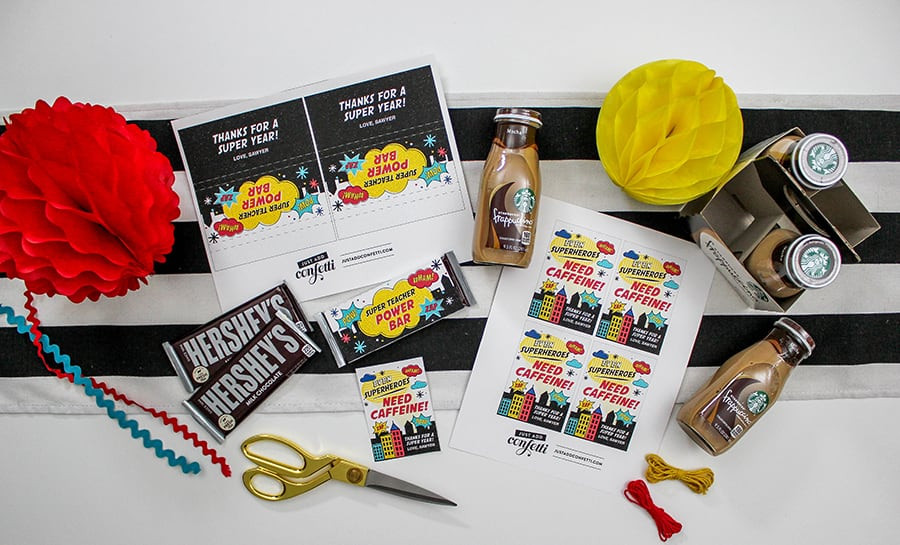 A gift bag with a superhero theme, containing a mug, a notebook, and a pen.