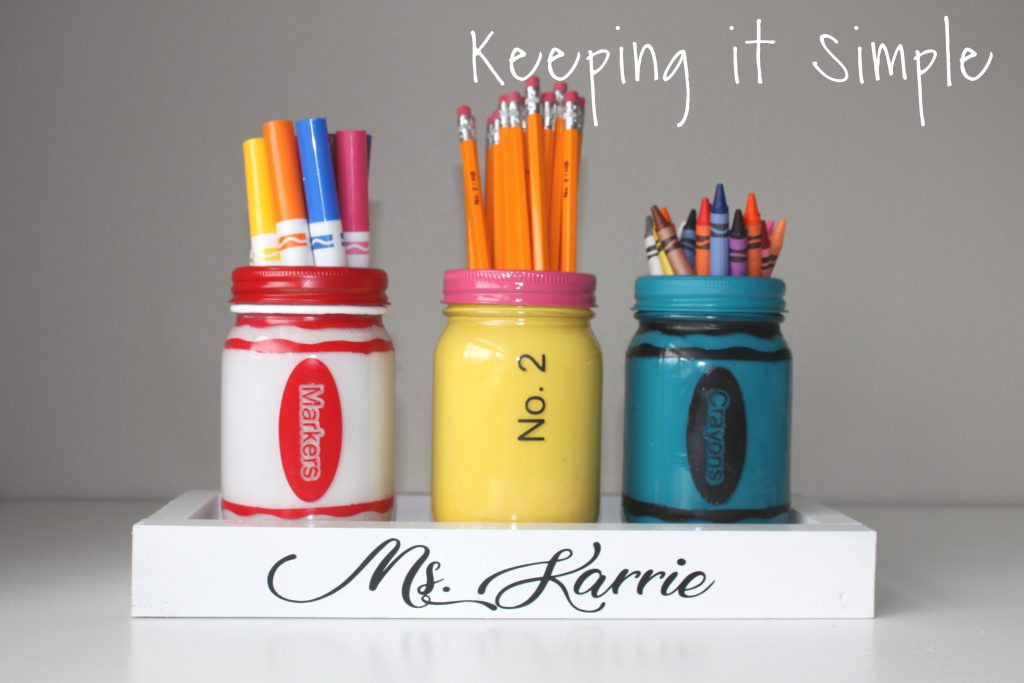 Alt: Colorful painted mason jars filled with school supplies like pencils, markers, and crayons, arranged on a white wooden tray.  Perfect for teacher appreciation gifts.