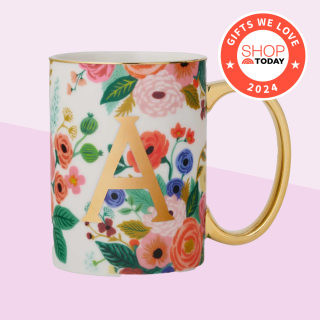alt text: A personalized monogram mug with a floral design sitting on a desk