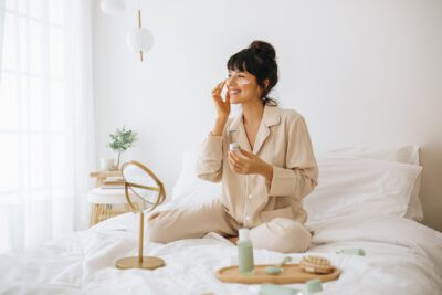 alt text describing an image of a smiling woman applying face cream
